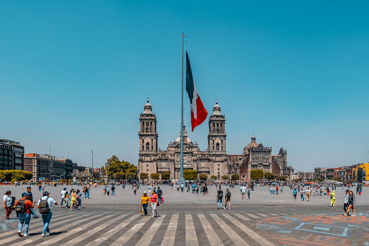 A bustling scene of Zócalo Square, Mexico City with the majestic Metropolitan Cathedral and vibrant activity.