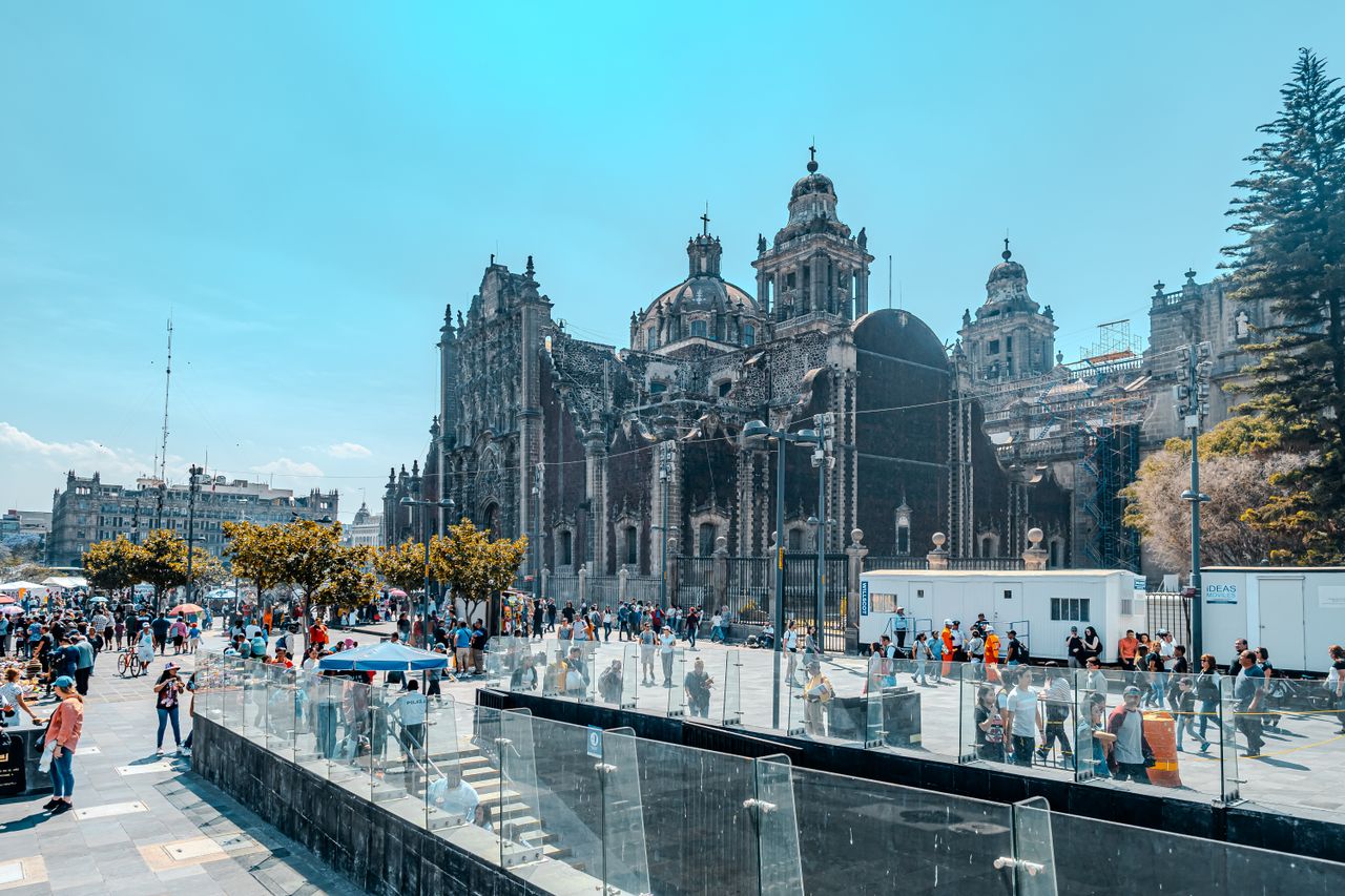 A bustling scene outside the iconic Metropolitan Cathedral in Mexico City, capturing urban life and architecture.
