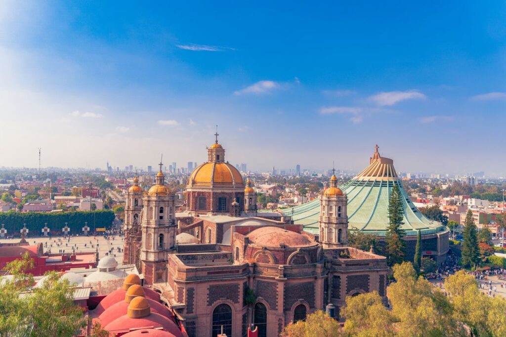Aerial view of the Basilica of Guadalupe and surroundings in Mexico City with a clear blue sky.