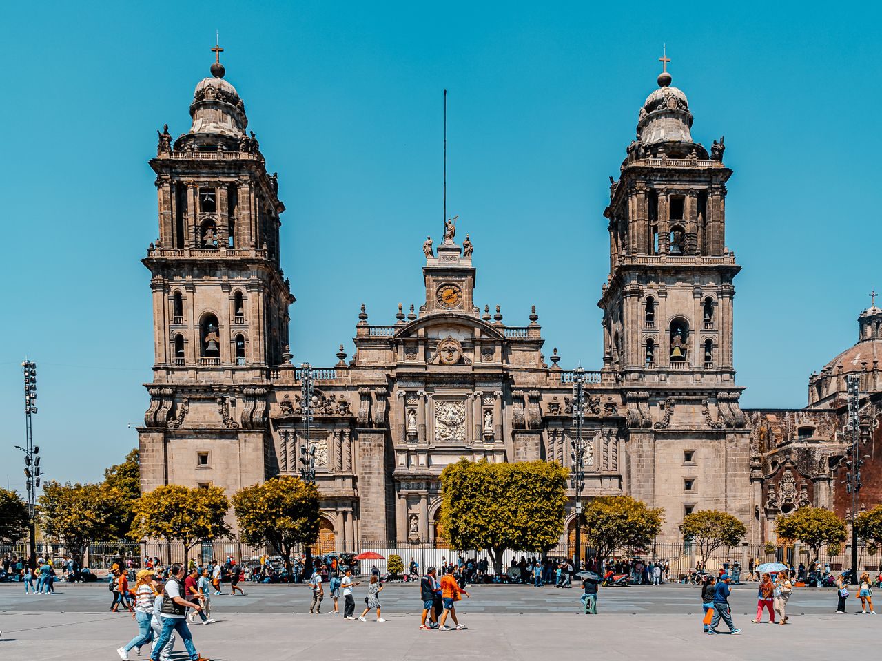Stunning view of the Metropolitan Cathedral in Mexico City with clear blue skies and bustling activity.